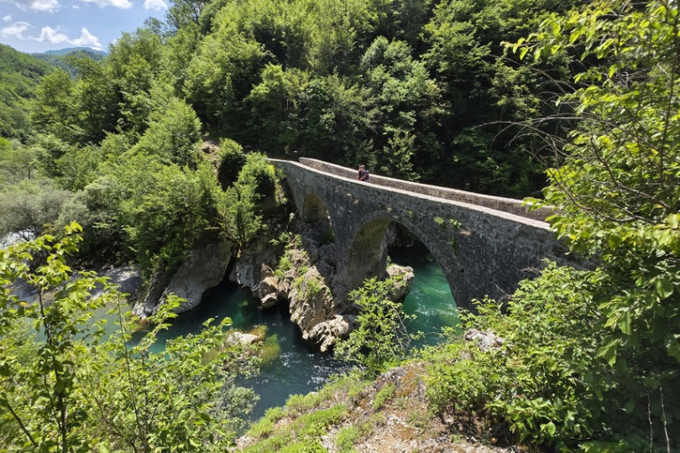 Twee reizigers staan op een brug in de natuur van Montenegro.