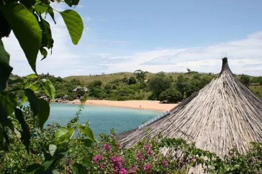Een rietendak van een huis met op de achtergrond een strand.