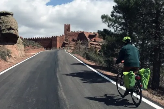 Fietsvakantie Aragón en Valencia - fietser in Peracense met kasteel op de achtergrond, Spanje.