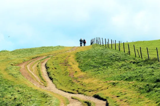 Twee wandelaren op een groene heuvel op een zonnige dag in Frankrijk.