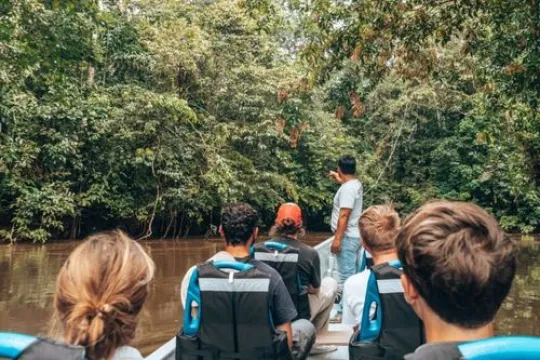 Familie die vaart in een boot over een rivier tussen de jungle.