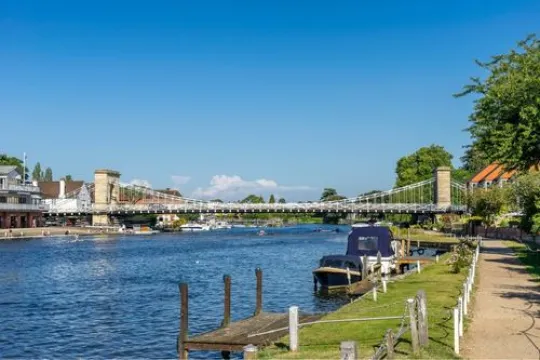 Een rivier met een hangbrug en bebouwing langs de oevers.