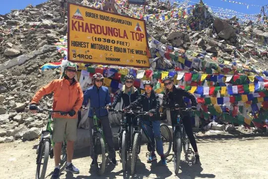 Ladakh trekking en biking - reizigers met fietsen bij de Khardungla top met vlaggetjes.